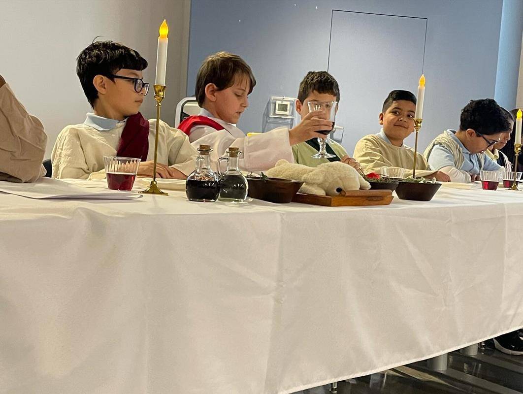 Students at Our Lady of the Assumption School gather for a Last Supper reenactment complete with a sacrificial lamb, bitter herbs and fresh greens.