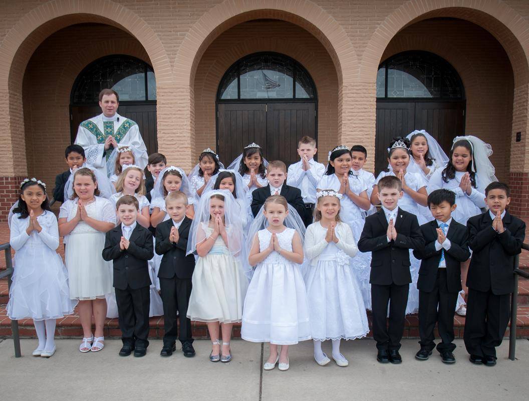 SALISBURY — Josephina Huynh receives her first Holy Communion from Father John Eckert, pastor, during Mass at Sacred Heart Church May 6. Also pictured is the entire class of first Communicants at the parish. (Photos by Bill Washington | Catholic News Hera