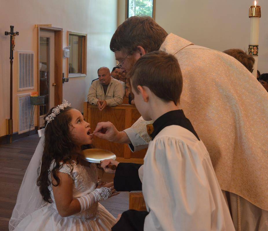 SYLVA — Fater Joshua Voitus, Pastor, of St Mary Catholic Church in Sylva, distributed First Holy Communion to 19 children on May 7. (Photo by Della Sue Bryson)